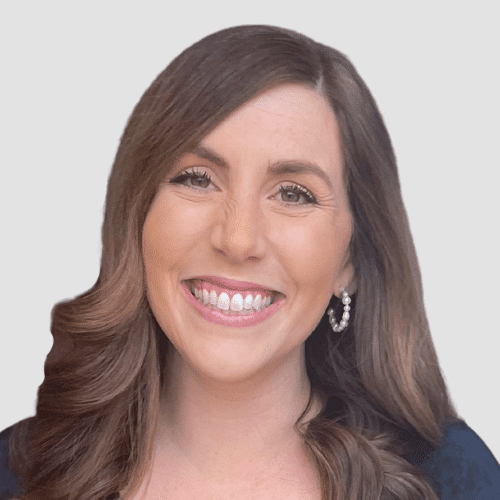 A woman with long hair smiling in front of a white background.