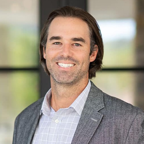 A man smiling in front of a window.
