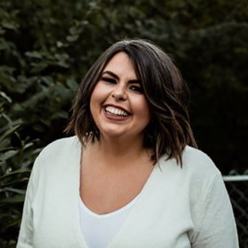 A smiling woman in a white v-neck sweater.
